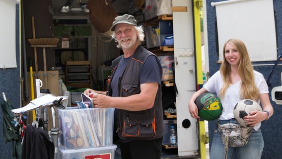 Zwei Filmteamarbeiter stehen vor einem offenem LKW. © NDR Foto: Claudia Timmann