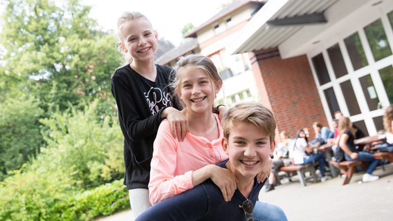 Luke Matt Röntgen trägt Marleen Quentin und Emilia Flint auf seinem Rücken. © NDR Foto: Claudia Timmann