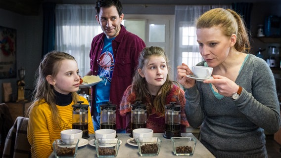 Maja (Annika Martens, rechts) hält eine Kaffeetasse. Alice (Emilia Flint, links), Mia (Marleen Quentin) und Sam (Ole Eisfeld) sehen zu ihr. © NDR/Studio HH Foto: Boris Laewen