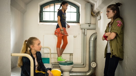 Kiara (Johanna götting, links), Lisha (Emma Roth) und Mia (Marleen Quentin) stehen in einer Gefängniszelle. © NDR/Studio HH Foto: Boris Laewen
