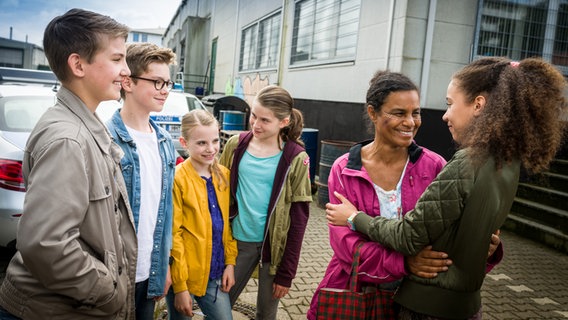 Anulika (Adisat Semenitsch, 2. von rechts) steht mit Johannes (luke Matt Röntgen), Benny (Ruben Storck), Alice (Emilia Flint), Mia (Marleen Quentin) und Lisha (Emma Roth) vor einem Haus. © NDR/Studio HH Foto: Boris Laewen