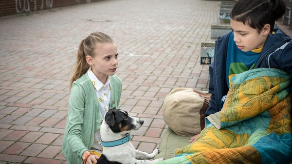 Alice (Emilia Flint) und Hund Murphy hocken vor Jamal (David Ganser), der auf einer Bank sitzt. © NDR/Studio HH Foto: Boris Laewen