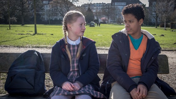 Tayo (Samuel Adams) sitzt mit Maja (Linnea Stolzenburg) auf einer Parkbank © NDR Foto: Boris Laewen