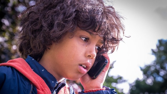 Femi telefoniert mit dem Handy und weint © NDR Foto: Boris Laewen