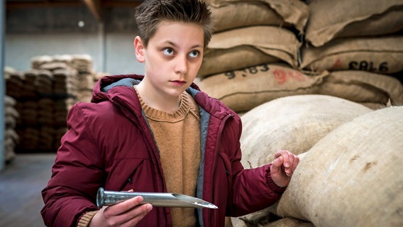 Moritz steht im Kakaolager und hält bei einer Stichprobe Kokain in den Händen. © NDR/Letterbox Foto: Boris Laewen