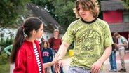 Jasina macht auf dem Schulhof eine abwehrende Handbewegung ihn Richtung eines Mitschülers. © NDR/Letterbox Foto: Boris Laewen