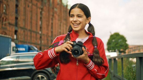 Jasina ist sehr fröhlich mit ihrer Fotokamera in der Speicherstadt unterwegs. © NDR/Letterbox 