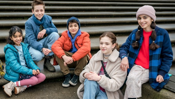 Die Pfefferkörner sitzen auf einer Treppe zum Gruppenfoto: Amy, Moritz, Hakim, Leo und Jasina. © NDR/Letterbox Foto: Boris Laewen