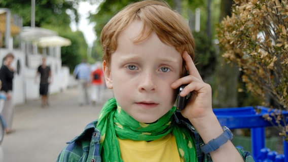 Henri hält ein Handy an sein Ohr © NDR/Letterbox Foto: Romano Ruhnau