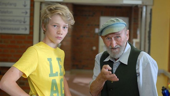 Max (Bruno Alexander) steht neben einem alten Mann mit Mütze (Hannes Stelzer). © NDR/Studio Hamburg Foto: Romano Ruhnau