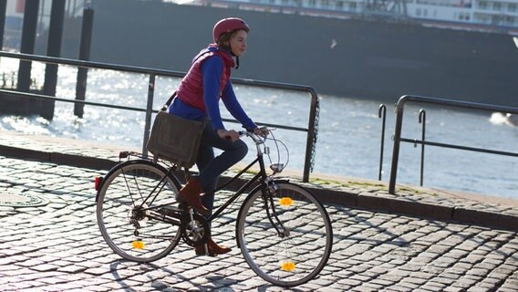 Tatja fährt mit dem Fahrrad am Hafen. © NDR Foto: Claudia Timmann