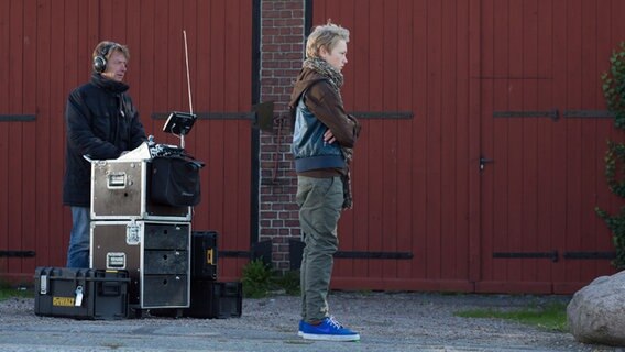 Max steht mit dem Rücken zu einem Mann mit Kopfhörern, der ein mobiles Tonmischpult bedient. © NDR Foto: Claudia Timmann