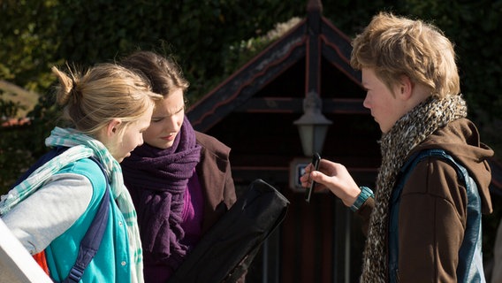 Max zeigt Jessi und Nina etwas auf seinem Handy. © NDR Foto: Claudia Timmann