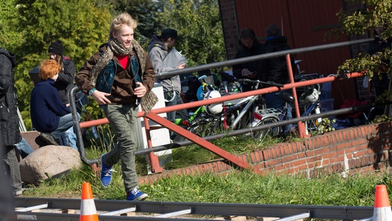 Max läuft mit Jacke und Schal neben Kameraschienen. © NDR Foto: Claudia Timmann