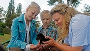 Sophie (Katherina Unger), Emma (Aurelia Stern) und die Tierärztin Frau Abraham mit einem Welpen. © NDR/Romano Ruhnau 