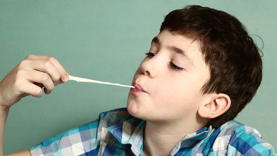 Junge zieht ein Kaugummi aus dem Mund. © Colourbox Foto: -