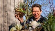 Gärtner Peter Rasch mit einem selbst gemachten Osterkörbchen in der Hand. © NDR Foto: NDR