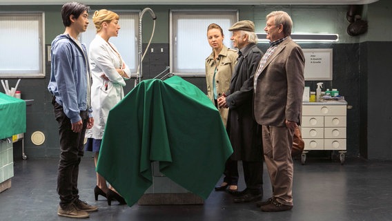 An seinem 70. Geburtstag sterben Achim Wagner und sein Schwiegersohn zeitgleich: beide fallen während des Essens tot in ihr Grillfleisch. Vicky Adam (Katja Danowski, 3.v.r.), denkt sofort an eine Lebensmittelvergiftung. Doch Dr. Rosalind Schmidts (Helene Grass, 2.v.l.) Opduktionsergebnisse geben Hui Ko (Aaron Le, l.), Edwin Bremer (Tilo Prückner, 2.v.r.) und Günter Hoffmann (Wolfgang Winkler, r.) neue Rätsel auf. © NDR/ARD/Kai Schulz 