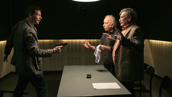 Während des Verhörs gelingt es dem Bankräuber Lutz Michel (Gerdy Zint, l.), Edwin (Tilo Prückner, 2.v.r.) und Günter (Wolfgang Winkler, r.), in der Wache als Geiseln zu nehmen. © NDR/ARD/Kai Schulz 