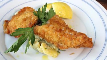 Mit Petersilie und Zitrone garnierter Backfisch und Kartoffelsalat auf einem Teller serviert. © NDR Foto: Florian Kruck