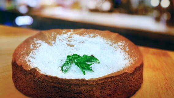 Mandeltorte mit Puderzucker bestäubt auf einem Holzbrett. © NDR Foto: Florian Kruck