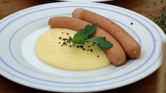 Zwei gekochte Würstchen mit Käse-Kartoffelpüree auf einem Teller © NDR Foto: Florian Kruck