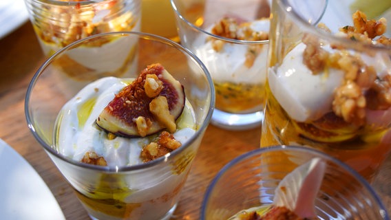Griechischer Joghurt mit Krokant, Früchten und frischen Feigen in einem hohem Glas geschichtet. © NDR Foto: Florian Kruck