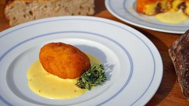 Mit Sardellenfilets oder Schinken gefüllte Kartoffel-Kroketten mit Aioli auf einem Teller serviert. © NDR Foto: Florian Kruck
