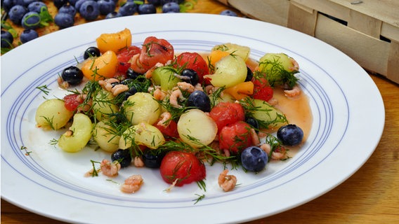 Ein Salat aus verschiedene Melonen-Sorten mit Krabben und Heidelbeeren auf einem Teller serviert. © NDR Foto: Florian Kruck