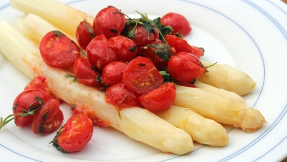 Weißer Spargel mit gebratenen Kirschtomaten auf einem Teller serviert. © NDR Foto: Florian Kruck