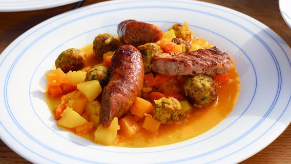 Steckrübeneintopf mit Möhren, Fleischklößchen, Schweinefilet und Bratwurst auf einem tiefen Teller serviert © NDR Foto: Florian Kruck