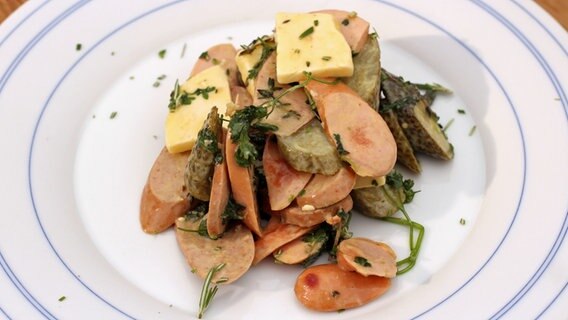 Wurstsalat mit Käse und Gurke auf einem Teller serviert. © NDR Foto: Florian Kruck