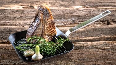Ein dickes Rindersteak mit Knochen steht senkrecht in einer Grillpfanne. © NDR Foto: Frank von Wieding