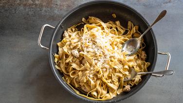 Tagliatelle in a pan sprinkled with cheese.  © NDR Photo: Frank von Wieding