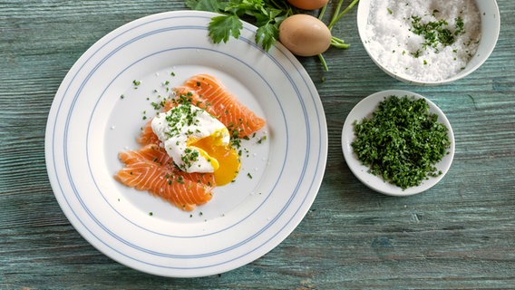 Lachscarpaccio mit pochiertem Ei auf einem Teller serviert. © NDR Foto: Frank von Wieding