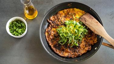 Pilz-Omelett mit Rucola bestreut in einer Pfanne. © NDR Foto: Frank von Wieding
