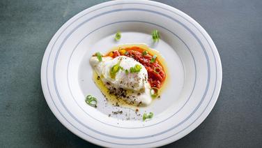 Ein pochiertes Ei mit zwei Soßen auf einem Teller serviert. © NDR Foto: Frank von Wieding