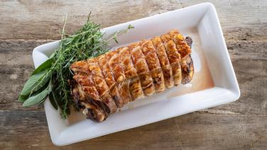 Ein ganzer Schweinerollbraten auf einer Platte serviert. © NDR Foto: Frank von Wieding