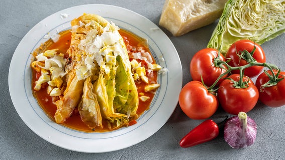 Geschmorter Spitzkohl mit Tomatensoße und Parmesan auf einem Teller serviert. © NDR Foto: Frank von Wieding