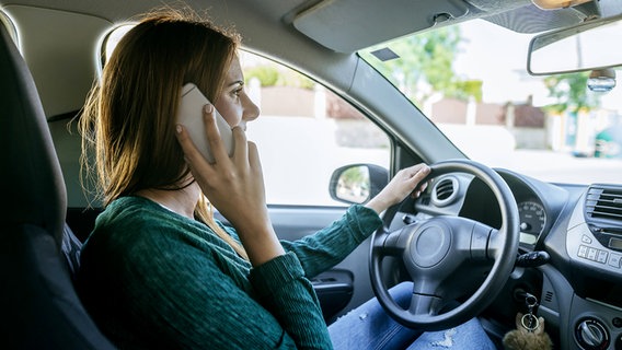 Eine Frau telefoniert während sie Auto fährt. © imago Foto: Westend61