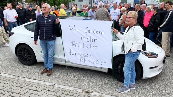 Zwei Personen halten ein Laken mit der Aufschrift "Wir fordern mehr Parkplätze für unsere Fahrschüler" hoch. © NDR Foto: Sören Gerhardt
