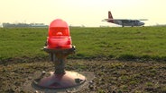 Ein Flieger des Ostfriesischen Flugdienstes landet im Hintergrund, im Vordergrund ist ein Warnlicht zu sehen © SH Magazin / NDR 