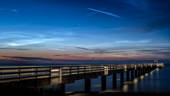 Eine Seebrücke steht unter einem leuchtenden Himmel um Mitternacht © Rainer Carlsdotter Foto: Rainer Carlsdotter