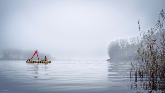 Passader See bei Nebel. Eone Schwimmplattform mit einer roten Rutsche liegt im Zentrum des Bildes. © Katja Habermann Foto: Katja Habermann