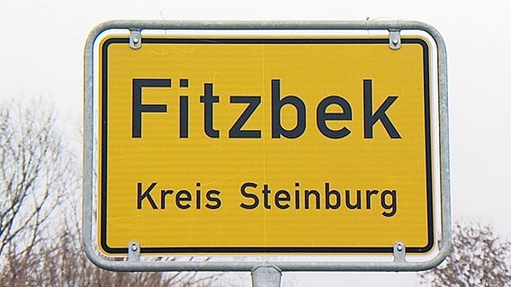 Das Ortsschild von Fitzbek steht vor grauem Himmel. © NDR 