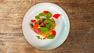 Gegrilltes Rumpsteak mit Auberginen-Petersilien-Soße und Kresseblüten auf einem Teller angerichtet. © NDR 