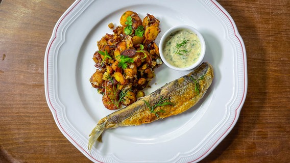 Fried fish with fried potatoes and tartar sauce is served on a plate.  © NDR/ SH Magazine 