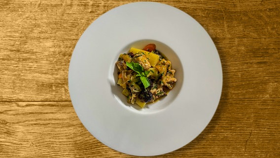 Rigatoni mit Oliven, Feigen und Kaninchen auf einem weißen Teller angerichtet. © NDR 