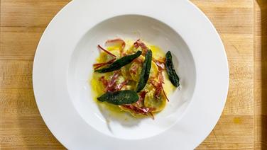 Ravioli with leaf spinach, ricotta and sage arranged on a plate.  © NDR 