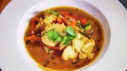 Red vegetable curry is served on a deep plate.  © NDR / SH Magazine 